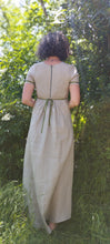 Charger l&#39;image dans la galerie, robe longue en lin beige, style regency, manche courtes, portées par Maureen, la creatrice de pret à porter, pieds nus dans l&#39;herbe