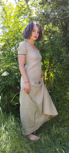 robe longue en lin beige, style regency, manche courtes, portées par Maureen, la creatrice de pret à porter, pieds nus dans l'herbe