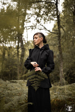 Charger l&#39;image dans la galerie, veste imperméable noir à capuche, portée par une jeune femme en forêt. Créaion Maureen Vinot pout la collection Sorcières