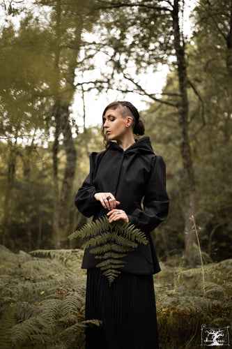 veste imperméable noir à capuche, portée par une jeune femme en forêt. Créaion Maureen Vinot pout la collection Sorcières