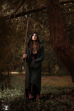 Charger l&#39;image dans la galerie, femme brune dans une forêt portant un long gilet à capuche gris sur une robe en velours lie de vin
Création Maureen Vinot