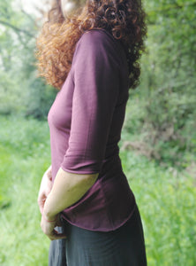 tee shirt bordeaux encolure ronde et manches trois quart. Porté par une femme rousse dans une prairie verdoyante. création Maureen Vinot