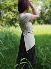 Charger l&#39;image dans la galerie, femme debout dans une prairie aux herbes hautes, elle porte un tee shirt en jersey beige. Ses cheveux auburn sont tressés.
Création Maureen Vinot