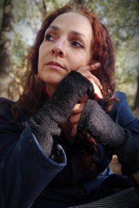 femme aux cheveux roux portant des mitaines en laine noires et un manteau imperméable bleu.