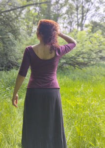 tee shirt bordeaux encolure ronde et manches trois quart. Porté par une femme rousse dans une prairie verdoyante. création Maureen Vinot