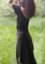 Charger l&#39;image dans la galerie, femme dans une prairie verdoyante, habillée avec un tee shirt dos nu noir et une jupe noire. Création Maureen Vinot