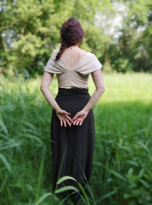 femme debout de dos dans une prairie aux herbes hautes, elle porte un tee shirt en jersey beige. Ses cheveux auburn sont tressés.
Création Maureen Vinot