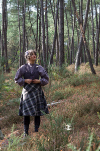 femme dans la forêt, jupe écossaise et veston en métis, teinture végétale violet/ aubergine foncé, et chemisier en lin par la créatrice Maureen Vinot
