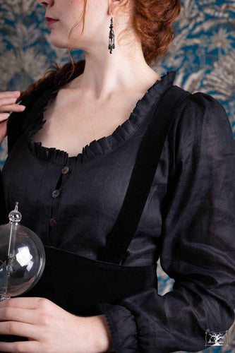 jeune femme rousse habillée d'un chemisier en lin noir porté avec une jupe tablier noire en velours. création créatrice Maureen